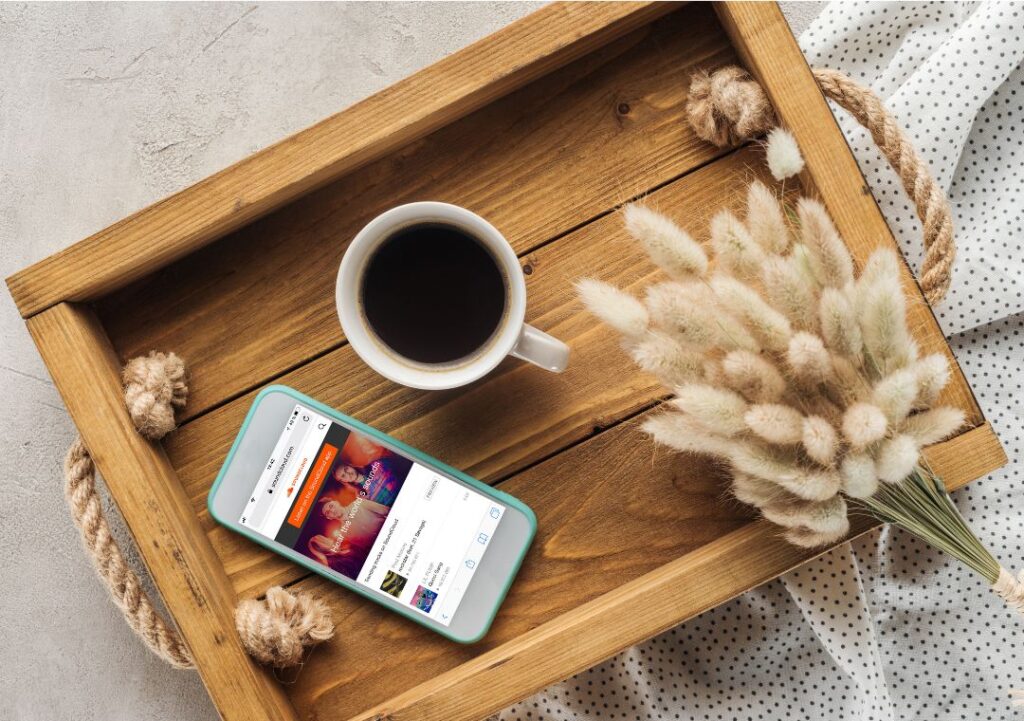 Top View of Cup of Coffee and Smartphone with Soundcloud Website on Screen on Tray with Lagurus