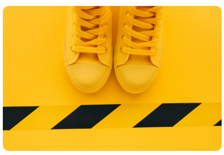 Overall yellow image showing sneakers behind a safety line. An image to go with text on brand safety.