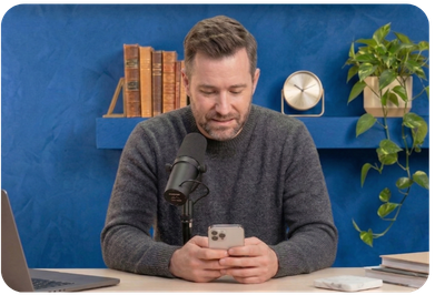 Podcast host looking down at his phone to read ad copy instead of looking into the camera