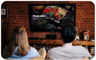 Two people watching a Netflix podcast on a large flat-screen TV in a modern living room
