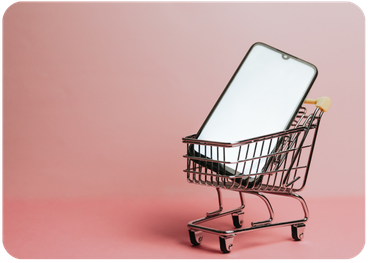 Miniature shopping cart holding a smartphone against a pink background