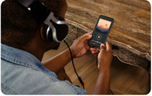 Person wearing over-ear headphones listening to a news podcast on a smartphone, illustrating how DTC brands are navigating podcast advertising during the 2026 midterm election ad spending surge