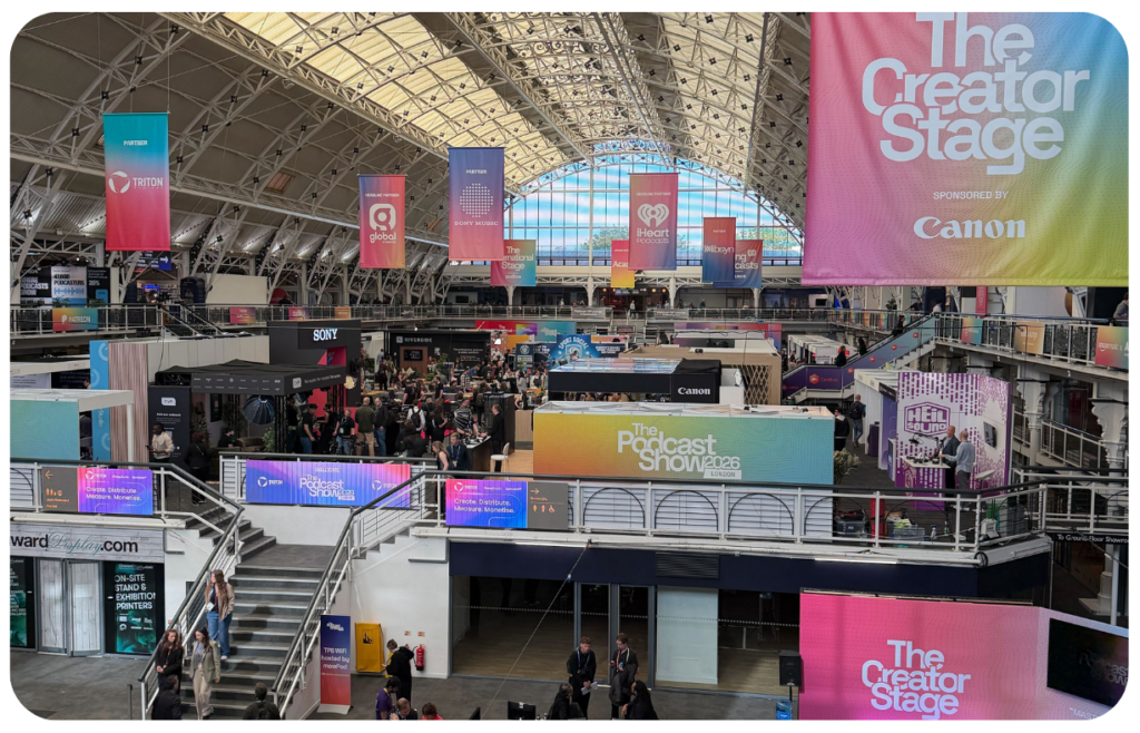The main hall at The Podcast Show 2026 in London, with the Creator Stage and partner banners overhead
