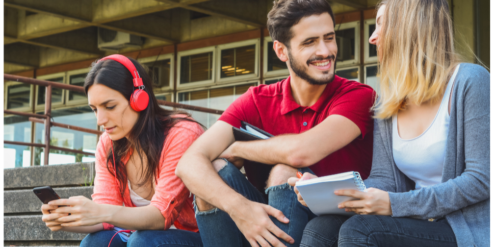 Young podcast listener wearing red headphones and using a smartphone while sitting with friends outdoors.