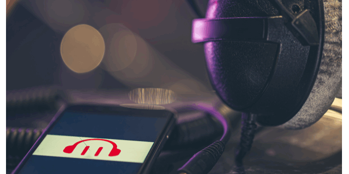 odcast studio scene showing microphone with purple lighting and smartphone displaying red arrow logo, representing podcast advertising and audio production.