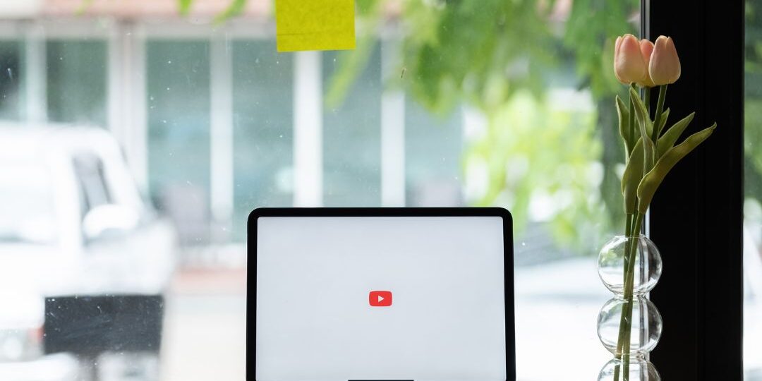 Laptop displaying YouTube logo in bright modern office workspace for planning YouTube sponsorship campaigns and creator partnerships