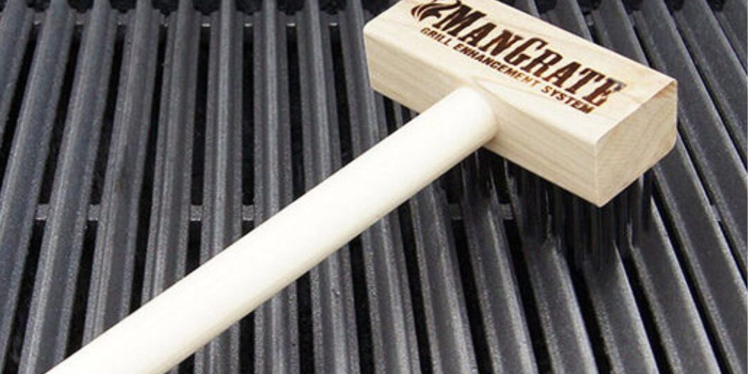 Mangrate cast iron grill enhancement system tool resting on grill grates, highlighting product advertised through podcast marketing.
